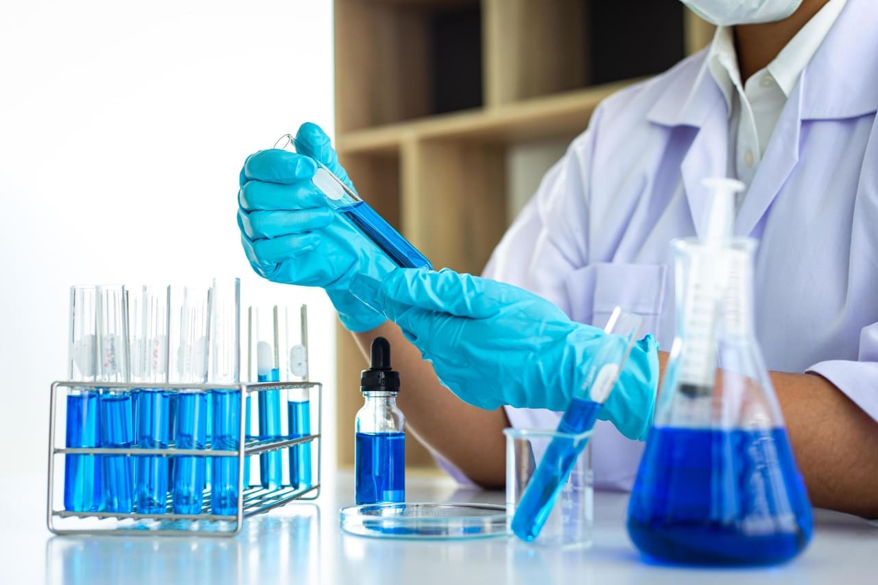 Lab scientist examining a test tube of blue reagent